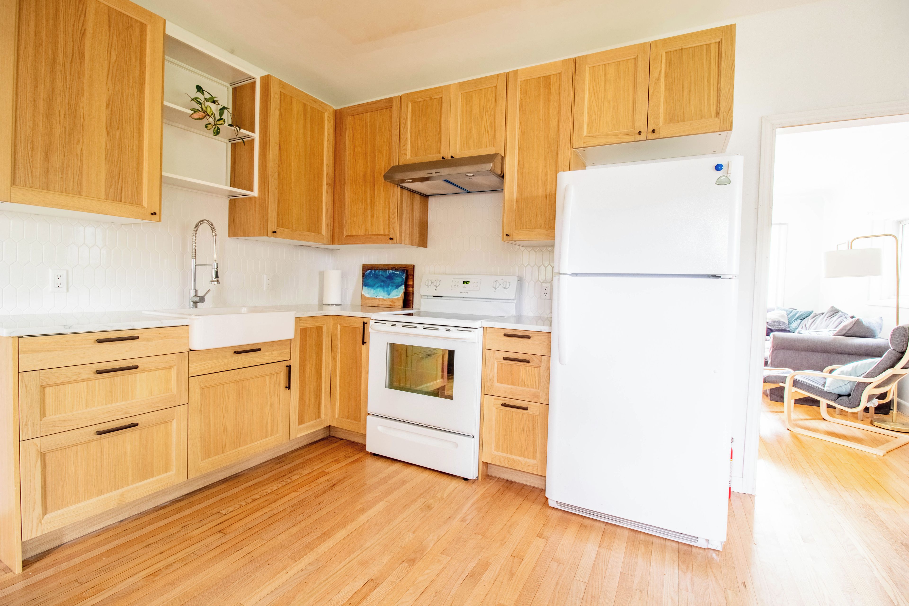 Une cuisine moderne avec des meubles en bois, un réfrigérateur blanc et une cuisinière.