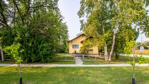 A yellow house with a small porch, surrounded by trees and a grassy yard.