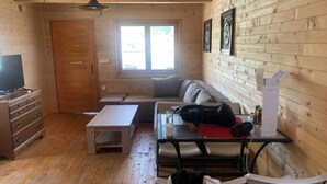 Une pièce confortable, aménagée comme un chalet, avec un intérieur en bois, un canapé, une table à manger et un téléviseur.