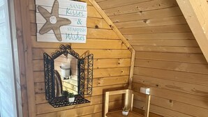 Une pièce mansardée chaleureuse avec des murs en bois, un panneau en forme d’étoile de mer, un miroir et une petite étagère.