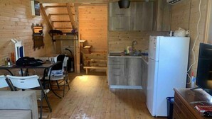 Une cuisine compacte avec des meubles en bois, un réfrigérateur blanc et un coin repas comprenant une table et des chaises.