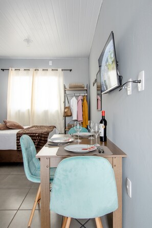 Cozy retreat with a neatly made bed, dining table, and mounted TV.
