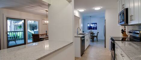 A modern kitchen with granite countertops, stainless steel appliances, and white cabinetry.