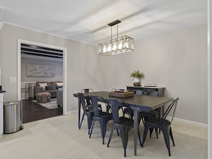 Un comedor moderno con una mesa de madera oscura y sillas a juego, una lámpara colgante y una planta en maceta al lado.