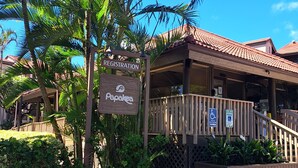 Une enseigne indiquant l’entrée d’un hôtel, avec un palmier et une terrasse couverte.