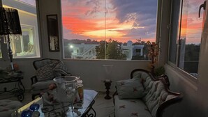 Una sala de estar con un ventanal grande, un sofá, una mesa con adornos y un sillón.