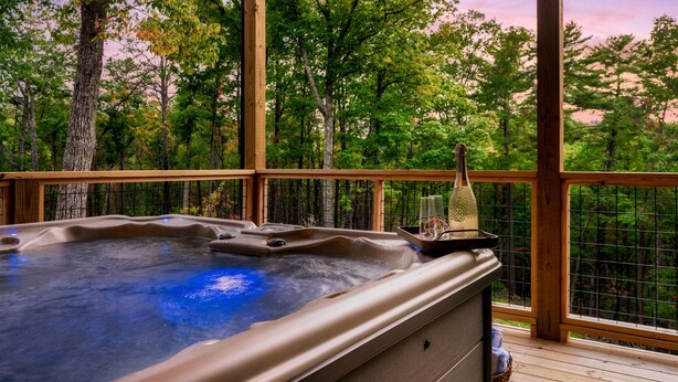 Ein Whirlpool auf einer Holzterrasse mit Blick auf einen Wald.