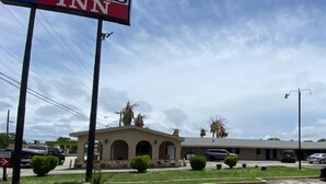 A Texas Inn sign with a clear view of the building's entrance and a parking lot. - Texas Inn (Seguin)