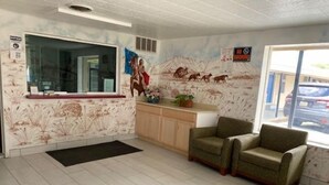 A reception area with a counter, a large window, and a mural of animals on the wall. - Texas Inn (Seguin)