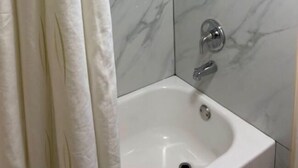 A bathroom with a shower enclosure, a sink, and a toilet. - Texas Inn (Seguin)