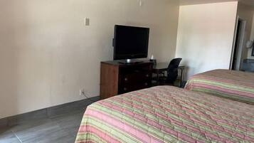 Una habitación de hotel con una cama, un televisor en una cómoda de madera y una silla.
