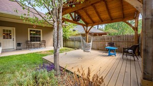 Een houten terras met een pergola, een hangmat en tuinmeubilair.
