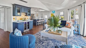 Een moderne keuken met donkerblauwe kastjes, een centraal kookeiland en een eethoek met witte stoelen.