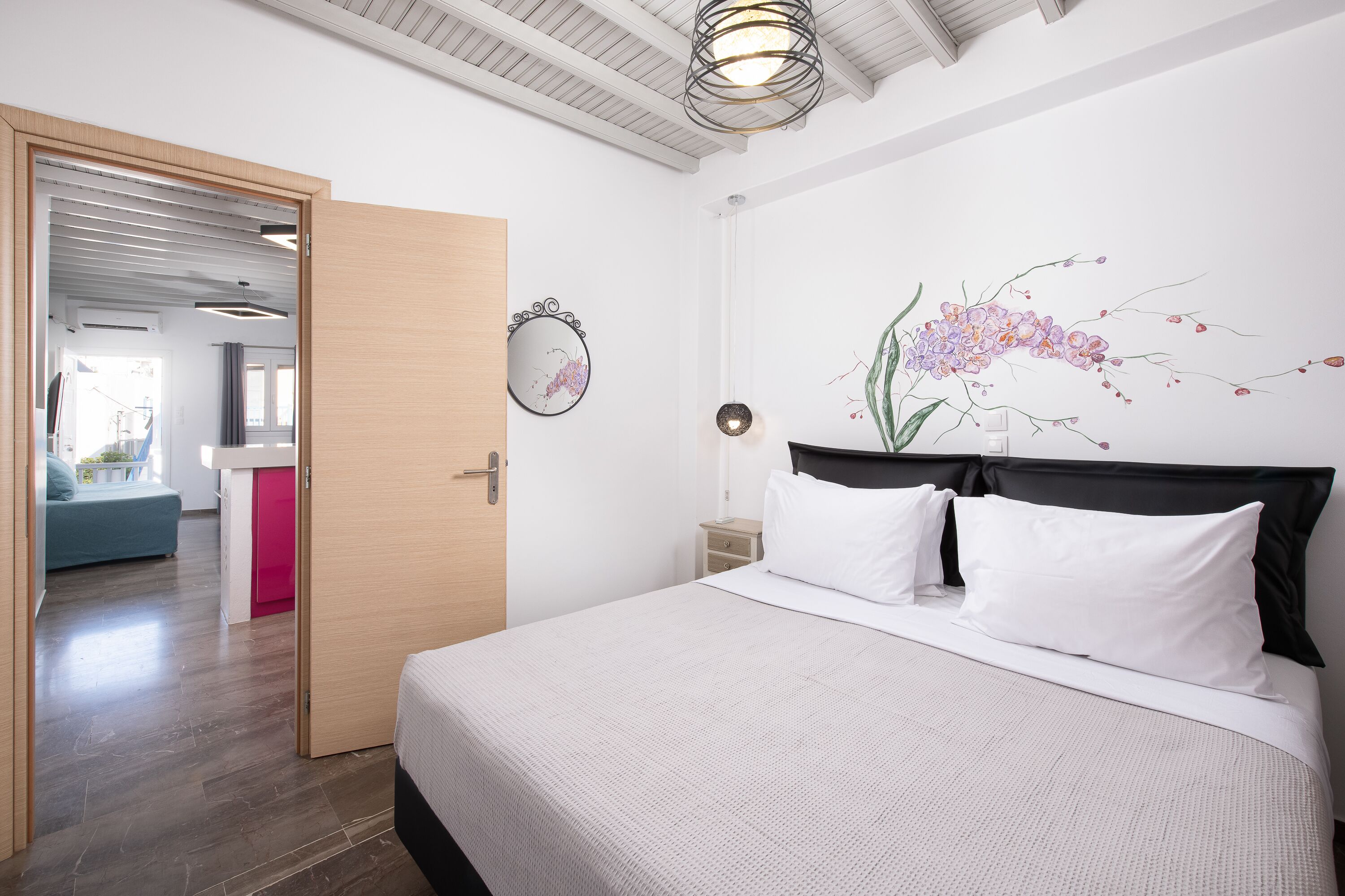 A bedroom with a bed, a wall-mounted mirror, and a floral mural.