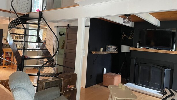 Een moderne woonkamer met een wenteltrap, een open haard en een televisie.