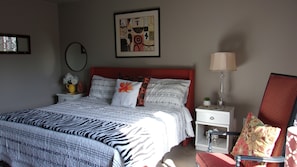 Quarto bem arrumado com colcha de padrão zebra, cabeceira vermelha e mesa de cabeceira com abajur.