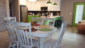 Une table à manger avec des chaises, un réfrigérateur, un four à micro-ondes et un évier dans une cuisine.