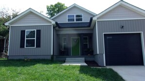 Une maison à deux étages avec un garage, un porche à l’avant et une porte verte.