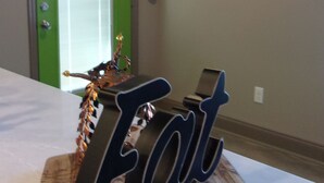 Une pièce comprenant une table sur laquelle est posé un panneau décoratif avec le mot « Manger », un extincteur et un tableau encadré accroché au mur.