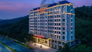 Ein mehrstöckiges Hotel mit einer markanten Kuppel auf dem Dach, genannt "RAMADA BY WYNDHAM".