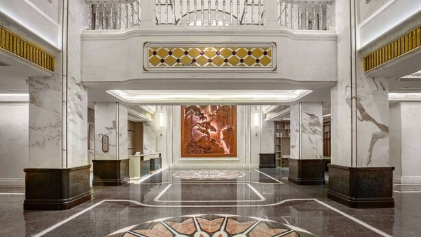 Eine prachtvolle Lobby mit Marmorböden, einer zentralen Dekoration und einer Treppe.