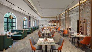 Ein geräumiges Restaurant mit hohen Tischen, grünen Sitzbänken, Marmorwänden und großen Fenstern.