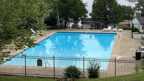A rectangular swimming pool with a black metal fence, surrounded by trees and a view of a lake and hills in the background. - Peacefull Lake Get-Away (Hot Springs)