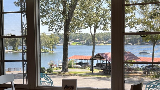 A table with a placemat and a small decorative item in a room with large windows overlooking a lake and park area. - Peacefull Lake Get-Away (Hot Springs)