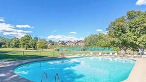 Ein Swimmingpool mit klarem, blauem Wasser, umgeben von Liegestühlen und einem Zaun.