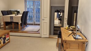 Huone, jossa on ruokapöytä, tuoleja, kirjahylly, työpöytä ja suuri peili.