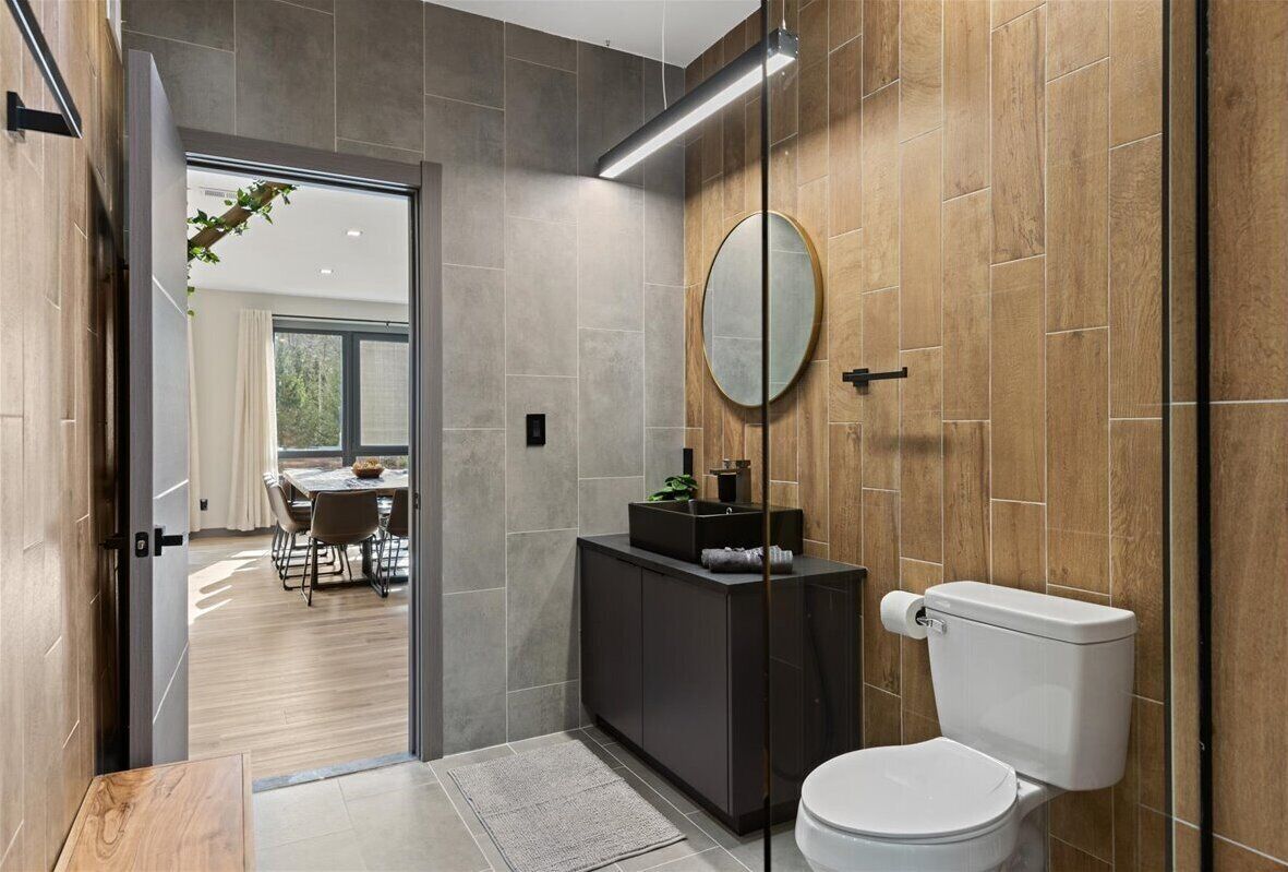 A modern bathroom with a toilet, a vanity with a mirror, and a shower area.