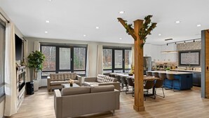 A modern living room with a fireplace, a dining area, and a kitchen with a bar.