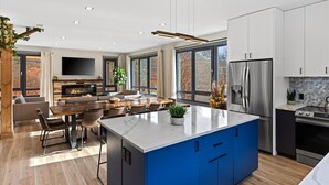 A modern kitchen with a central island, built-in appliances, and large windows.