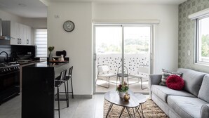 A modern kitchen with a dining area, a sofa, and a balcony with a view. - City Center Piantini W/ Pool, WiFi By YellowKey (Santo Domingo)