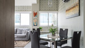 A modern dining area with a glass table and black chairs, a gray sofa, and a decorative plant. - City Center Piantini W/ Pool, WiFi By YellowKey (Santo Domingo)