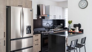 A modern kitchen with stainless steel appliances, a gas stove, and a central island with bar seating. - City Center Piantini W/ Pool, WiFi By YellowKey (Santo Domingo)