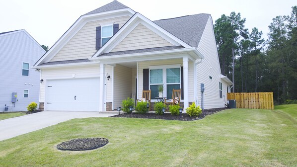 A two-story house with a front porch, a garage, and a well-maintained lawn.