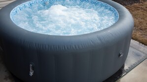 En oppustelig jacuzzi med blå mosaikfliser indeni, en reguleringsventil og en pumpebase.