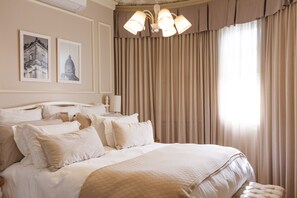 A well-appointed hotel room with a large bed, multiple pillows, a chandelier, and two framed pictures on the wall. - Hotel Casacurta (Garibaldi)