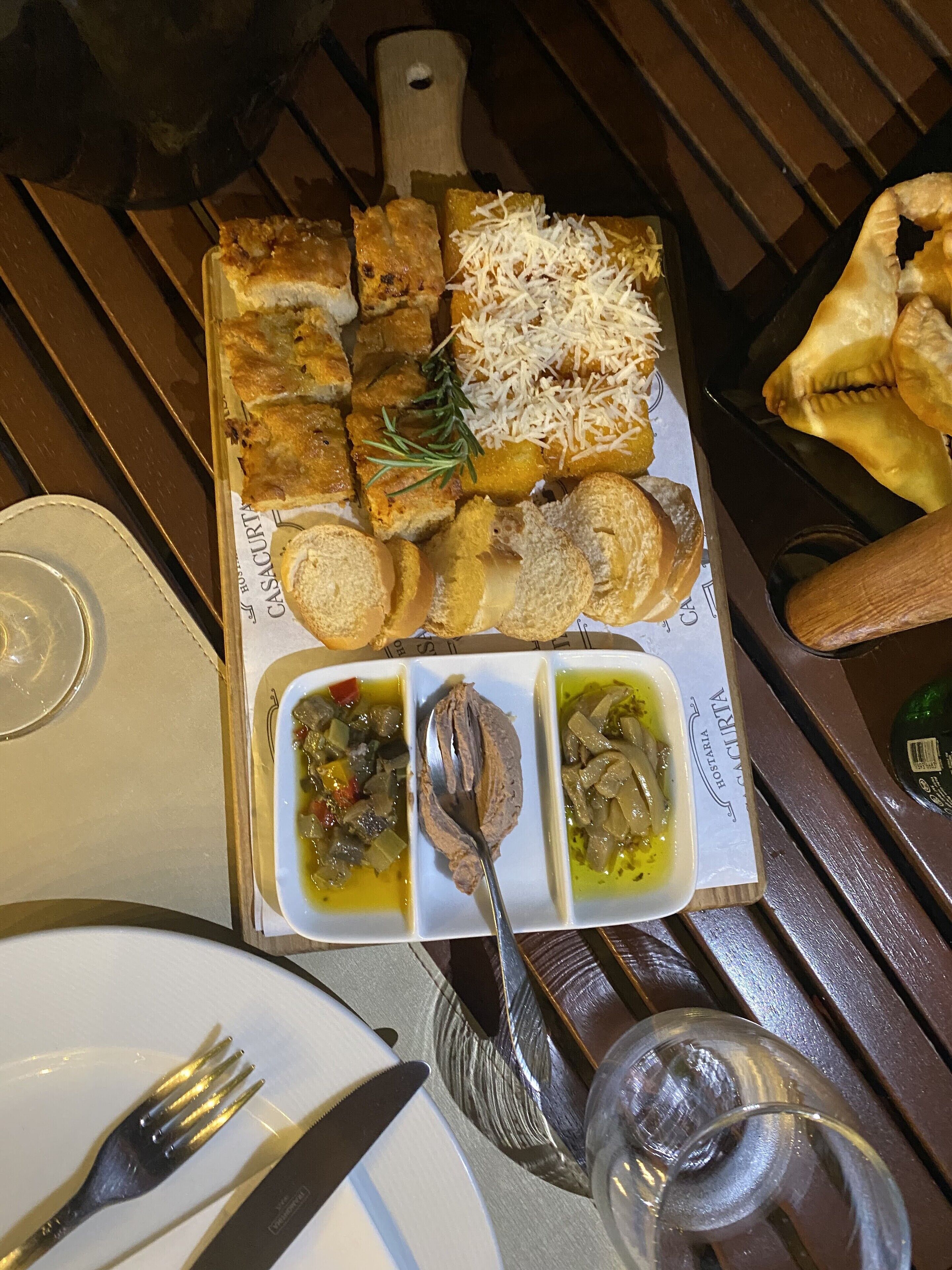 A wooden table with a tray of food including bread, cheese, and dips.