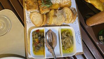 A wooden table with a tray of food including bread, cheese, and dips.