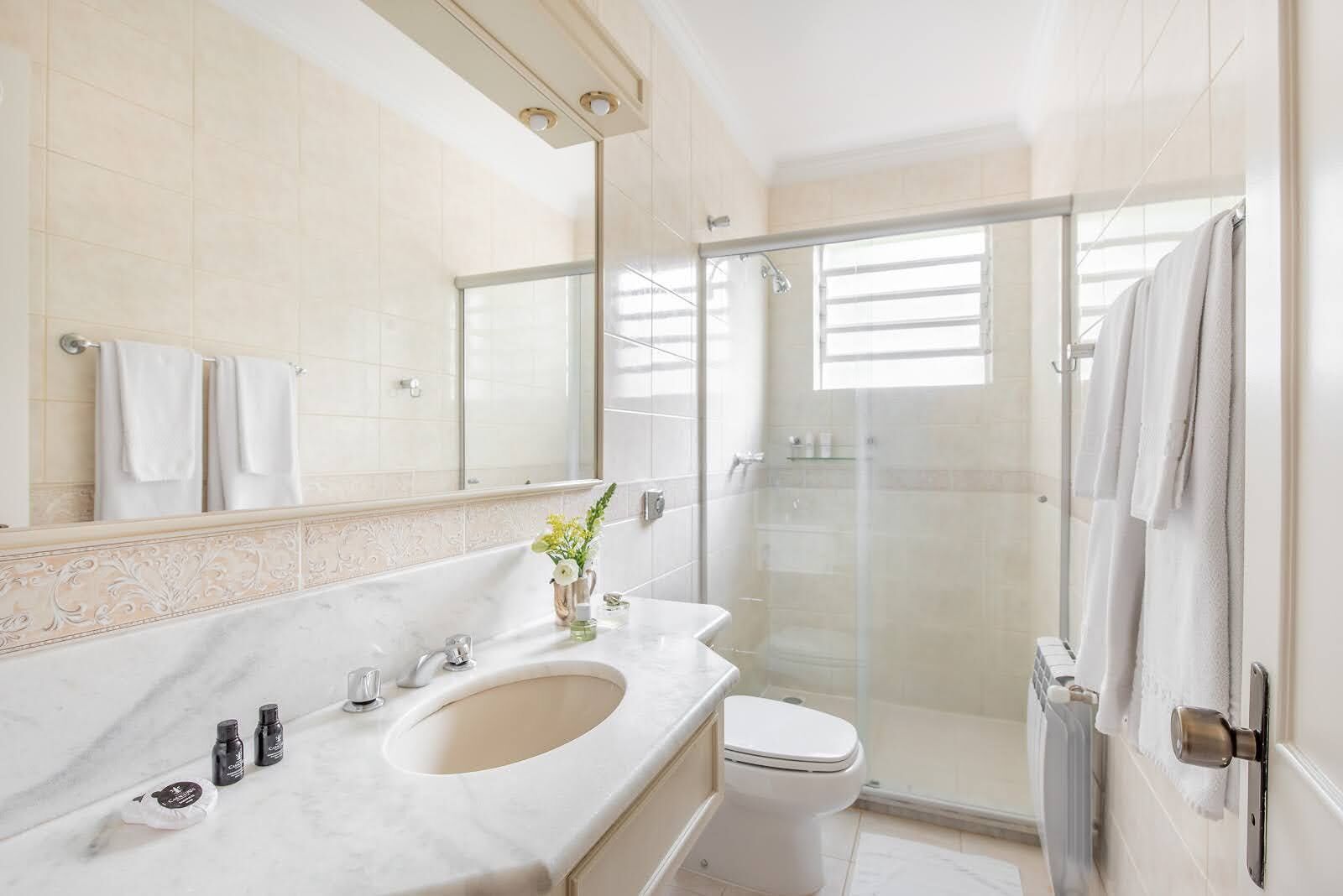 A modern bathroom with a marble sink, a glass shower enclosure, and a toilet.