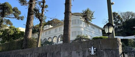 Un muro de piedra con un letrero del Hotel Casacurta, rodeado de árboles y un edificio al fondo.