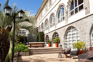 A courtyard with a stone building, outdoor seating, and potted plants. - Hotel Casacurta (Garibaldi)