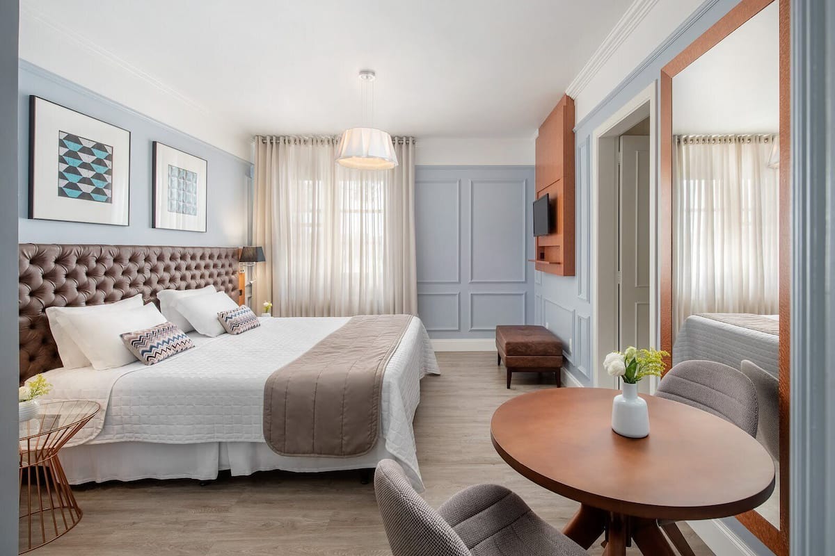 A hotel room with a large bed, a round table, and a TV mounted on the wall.