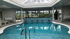 Una piscina interior con suelo de baldosas y techo de cristal.