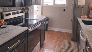 A modern kitchen with dark cabinetry, a stainless steel stove, and a wooden floor. - Full of Character and Convenient to Downtown and HPU.    (High Point)