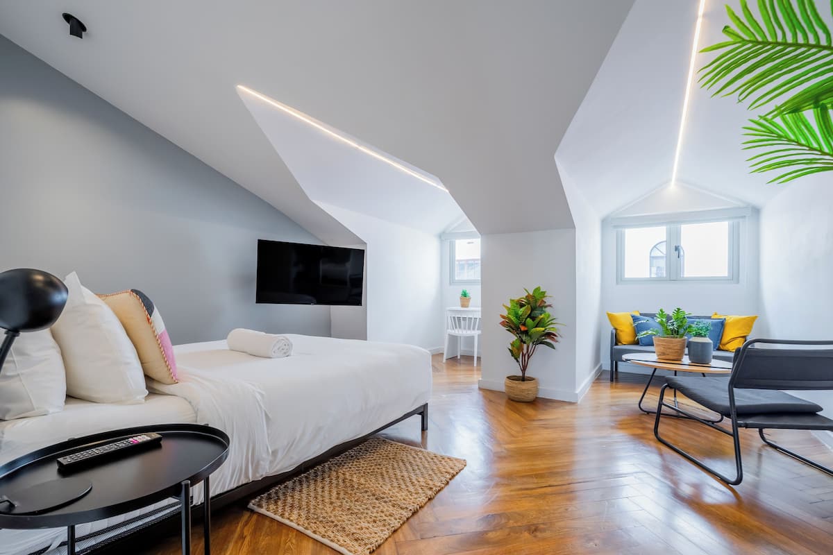 Une chambre à coucher moderne avec un lit, une table de chevet et un téléviseur fixé au mur.