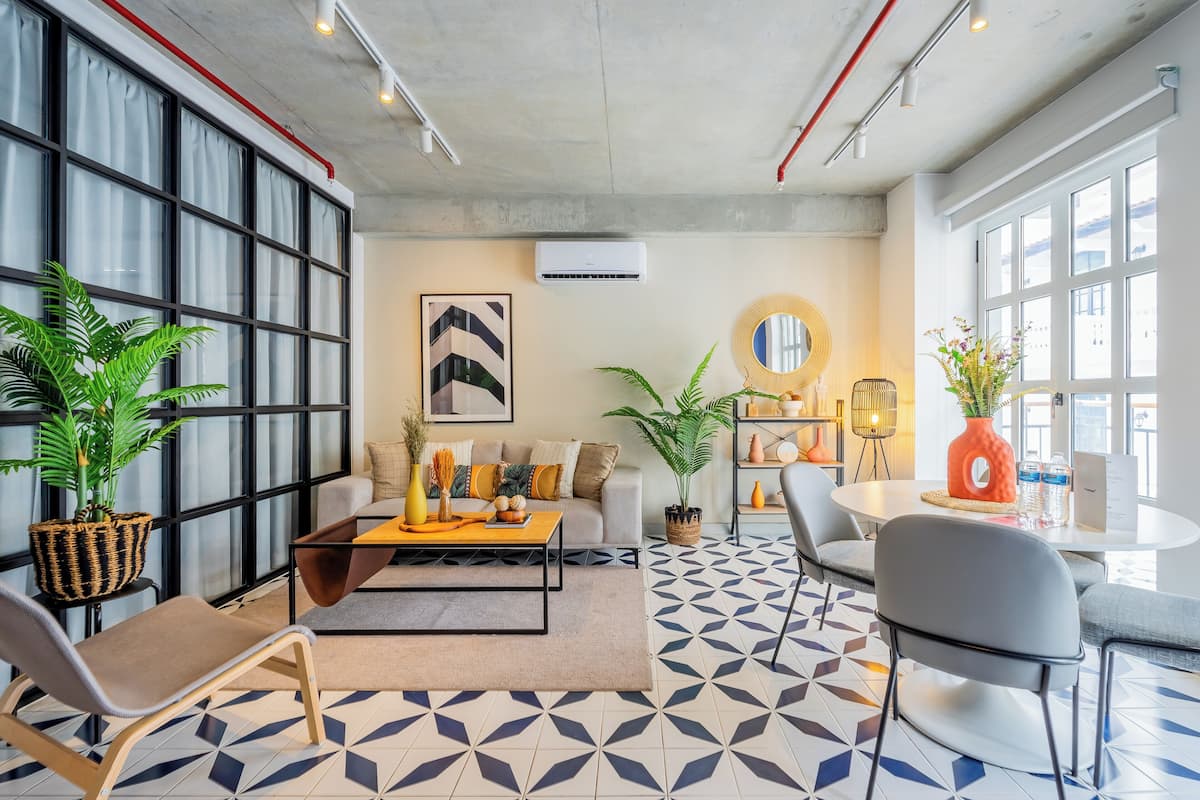 Un salon moderne avec un canapé, une table basse et des fauteuils, un sol à motifs et de grandes fenêtres.