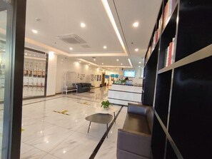 Un moderno vestíbulo de hotel con una recepción, zona de estar y una estantería.